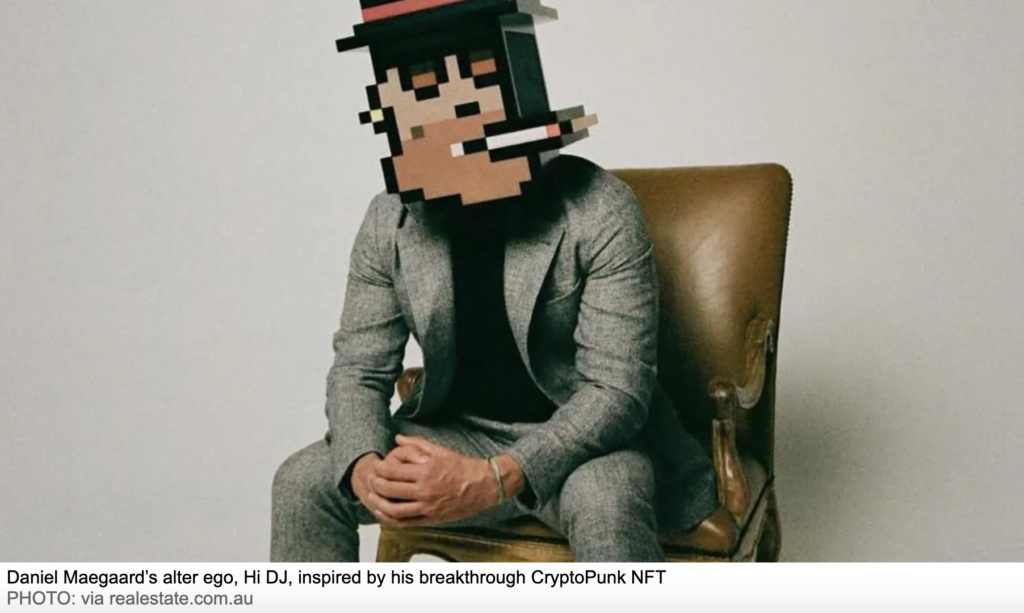 A man in a grey suit sits on a vintage leather chair against a plain background. His head is digitally replaced with a pixelated CryptoPunk NFT featuring a hat and cigarette. The caption identifies him as Daniel Maegaard’s DJ alter ego, inspired by his CryptoPunk.