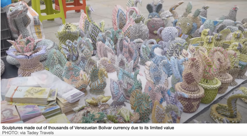 A display of intricate animal and floral sculptures made from thousands of folded Venezuelan Bolivar banknotes. Stacks of unused notes sit in the foreground, symbolising the currency’s collapse — a stark contrast to those looking to buy Bitcoin with a crypto SMSF in Australia as a hedge against inflation.